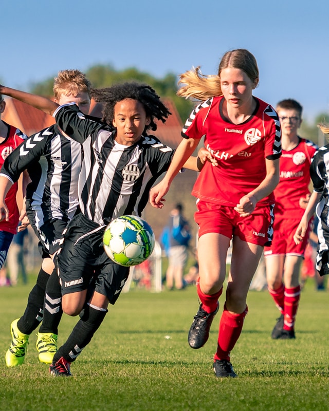 Group of people playing football on a green grass pitch